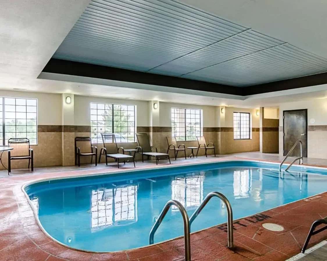 a large pool in a hotel room with chairs and tables at Comfort Inn & Suites Lawrence - University Area in Lawrence