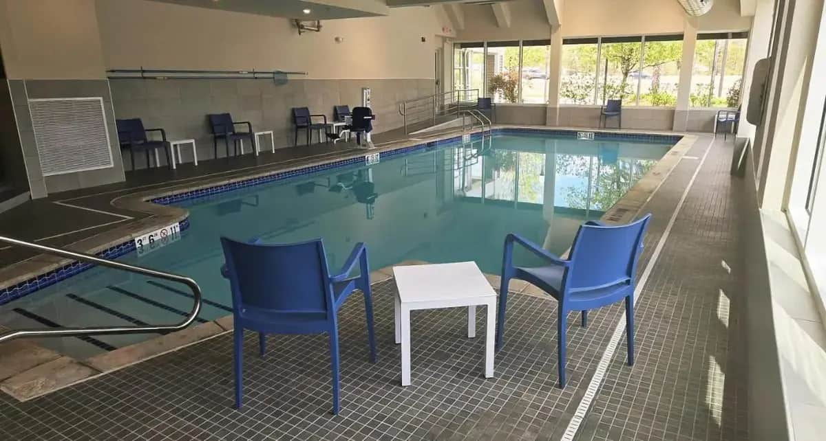 a swimming pool with blue chairs and a table in it at Comfort Inn Concord South End in Concord