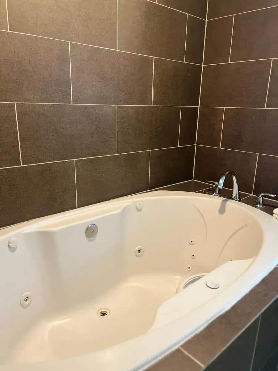 a white bath tub in a bathroom with a tile wall at Comfort Suites Denver International Airport in Denver