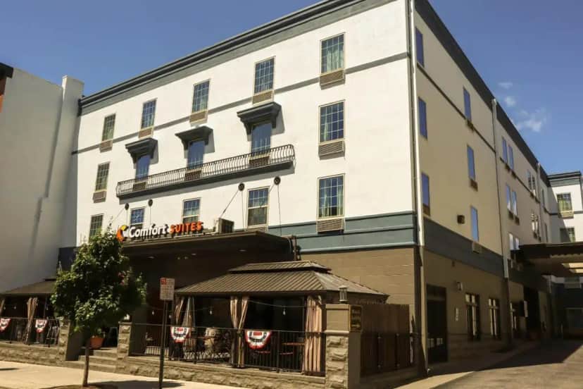 a large white building with a restaurant in front of it at Comfort Suites Downtown Carlisle in Carlisle