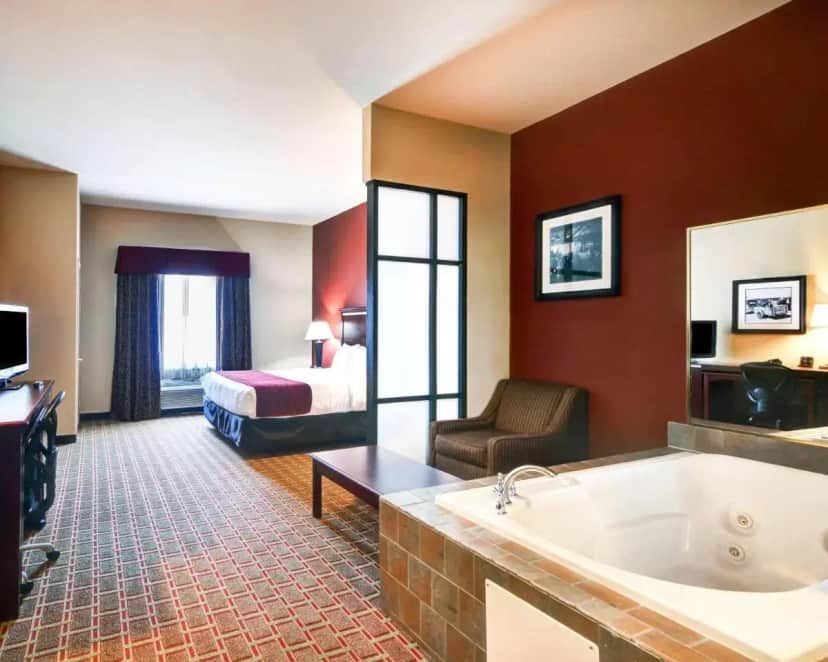 a hotel room with a tub and a bed at Comfort Suites Lake Worth in Fort Worth