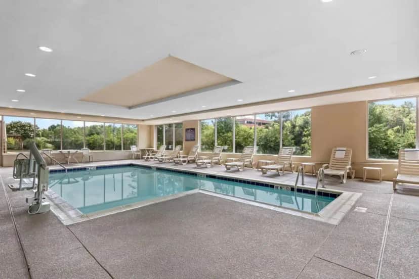 a pool in a hotel room with chairs and tables at Comfort Suites Manassas Battlefield Park in Manassas