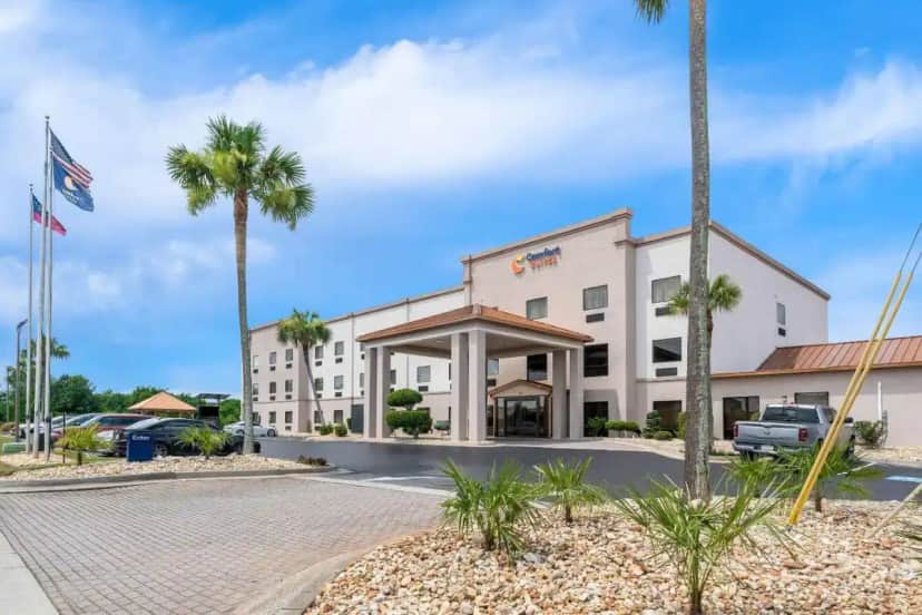 a hotel with palm trees in front of it at Comfort Suites near Robins Air Force Base in Warner Robins