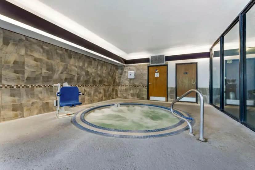 a hot tub in a room with a blue chair at Comfort Suites Near Vancouver Mall in Vancouver