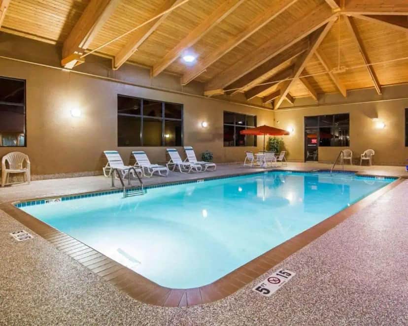 a large pool in a hotel with chairs and tables at Comfort Suites Ramsey in Ramsey