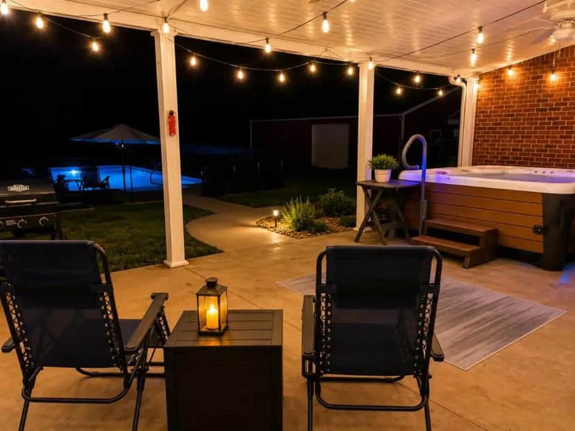 a patio at night with a hot tub and chairs at Country Getaway with Pool, Hot Tub, Star Wars Movie & Game Rooms! in Portland