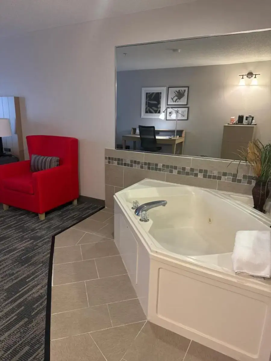 a large bathroom with a tub and a red chair at Country Inn & Suites by Radisson, Elgin, IL in Elgin