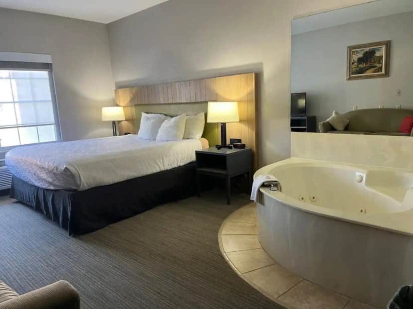 a hotel room with a bed and a bath tub at Country Inn & Suites by Radisson, Minneapolis-Shakopee in Shakopee