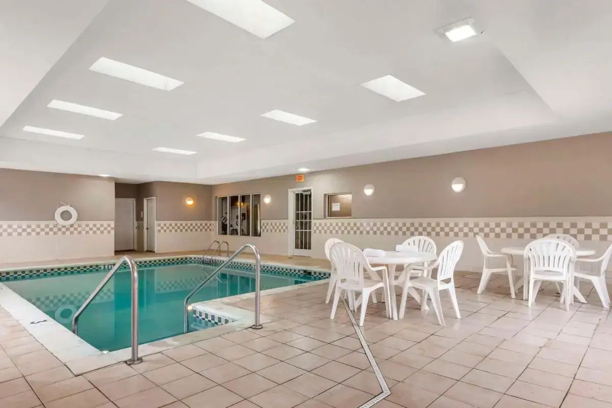 a pool with a table and chairs next to a table and a pool at Country Inn & Suites by Radisson, Newport News South, VA in Newport News
