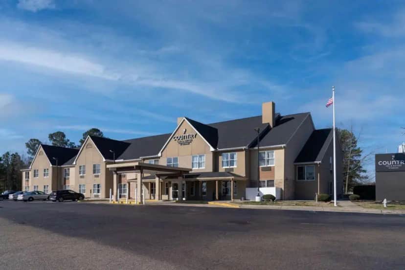 a large building with a flag in front of it at Country Inn & Suites by Radisson, Richmond I-95 South, VA in Richmond