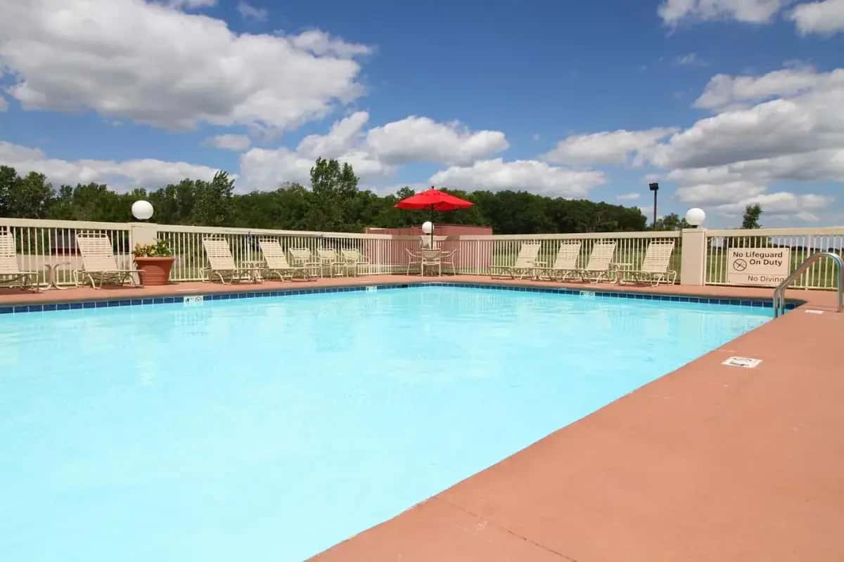 a large swimming pool with chairs and a red umbrella at Country Inn & Suites by Radisson, Sandusky South, OH in Milan