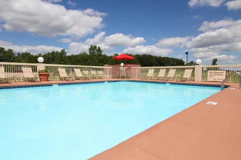 a large swimming pool with chairs and a red umbrella at Country Inn & Suites by Radisson, Sandusky South, OH in Milan