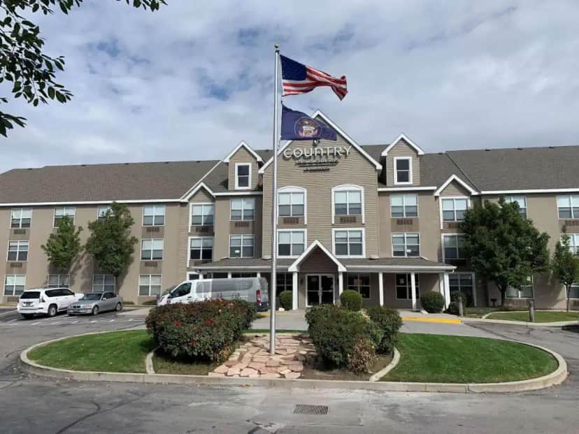 a hotel with an american flag in front of it at Country Inn & Suites by Radisson, West Valley City, UT in West Valley City