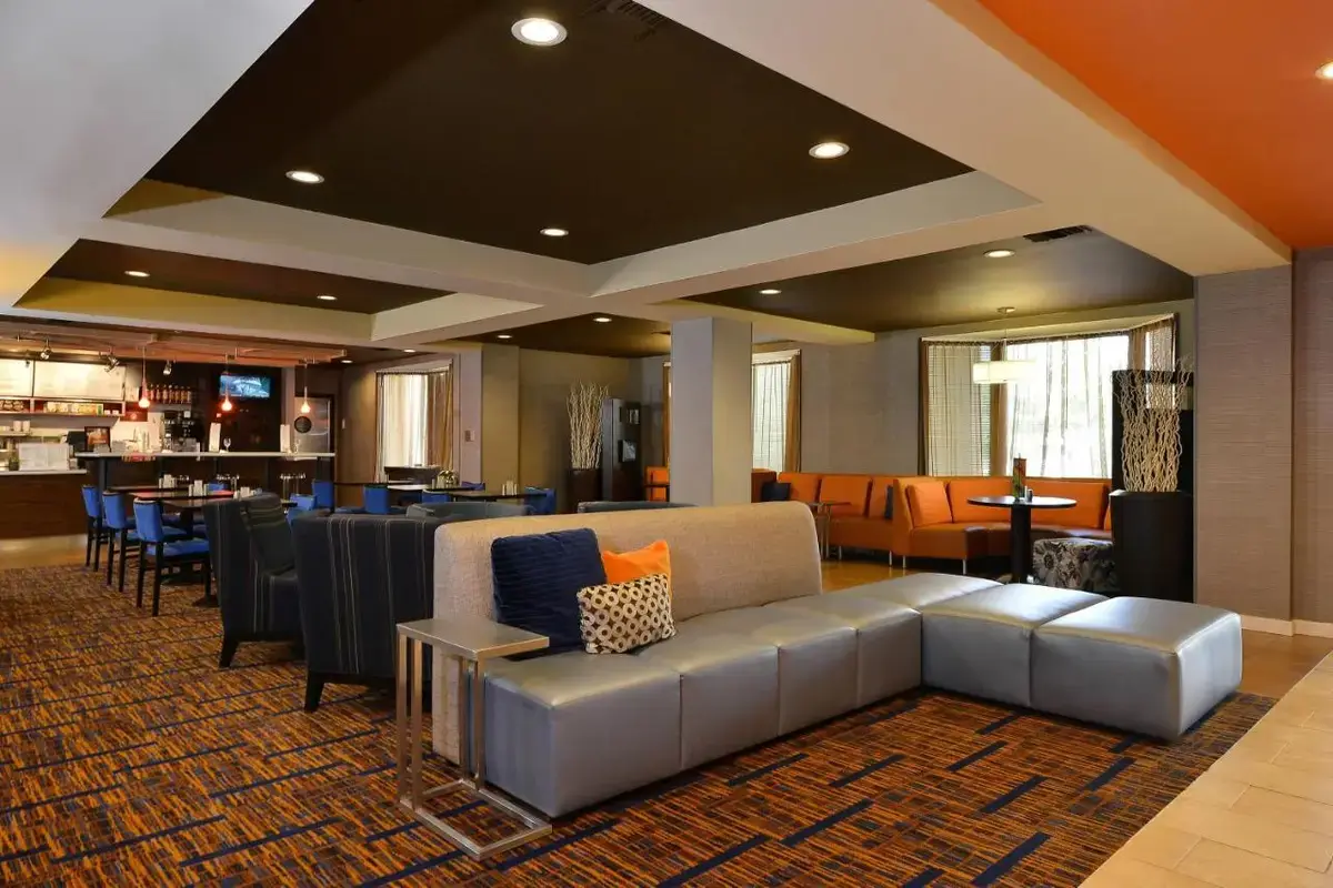 a lobby with a couch and chairs and a restaurant at Courtyard by Marriott Bentonville in Bentonville