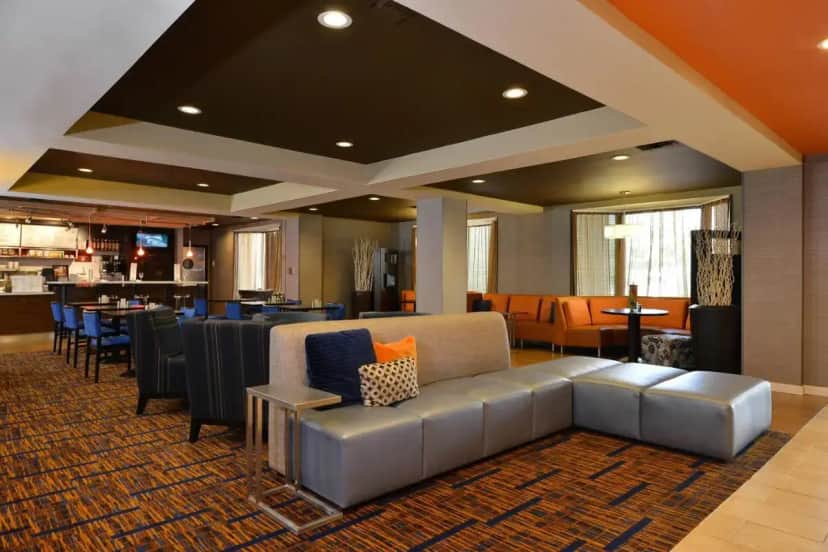 a lobby with a couch and chairs and a restaurant at Courtyard by Marriott Bentonville in Bentonville