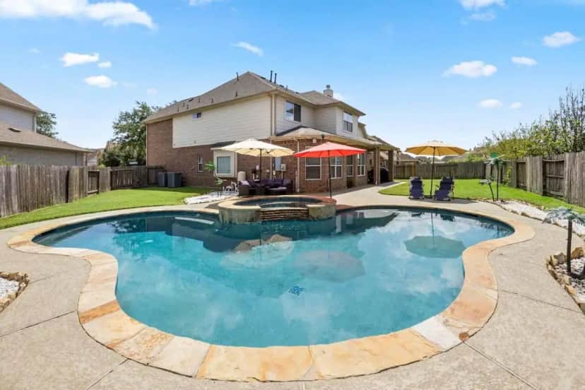 a swimming pool in the backyard of a house at Cozy Home in Houston with heated pool and hot tub in Houston