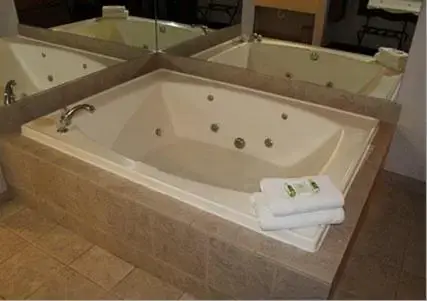 a large bath tub with two towels in a bathroom at Crown Choice Inn & Suites Lakeview and Waterpark in Mackinaw City