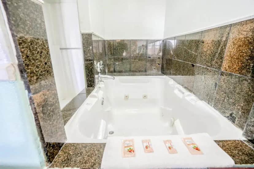a white bath tub in a bathroom with tiles at Day & Night Inn in Hesperia