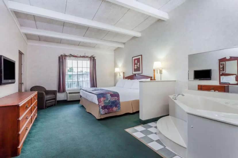 a hotel room with a bed and a sink at Days Inn & Suites by Wyndham Lexington in Lexington