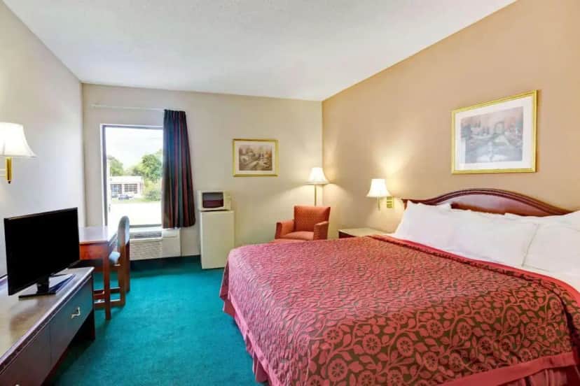 a hotel room with a bed and a television at Days Inn & Suites by Wyndham Louisville SW in Louisville