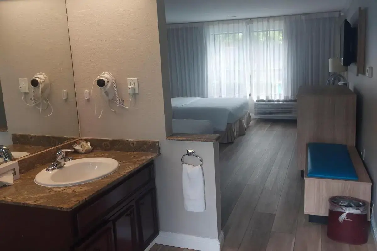 a bathroom with a sink and a bed and a mirror at Days Inn & Suites by Wyndham Mountain View in Mountain View