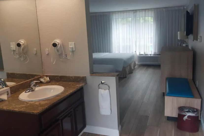 a bathroom with a sink and a bed and a mirror at Days Inn & Suites by Wyndham Mountain View in Mountain View