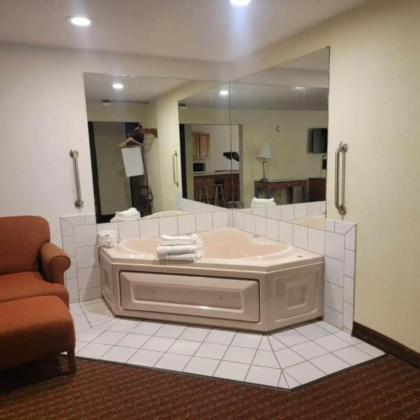 a bathroom with a tub and a large mirror at Days Inn by Wyndham Fort Dodge in Fort Dodge