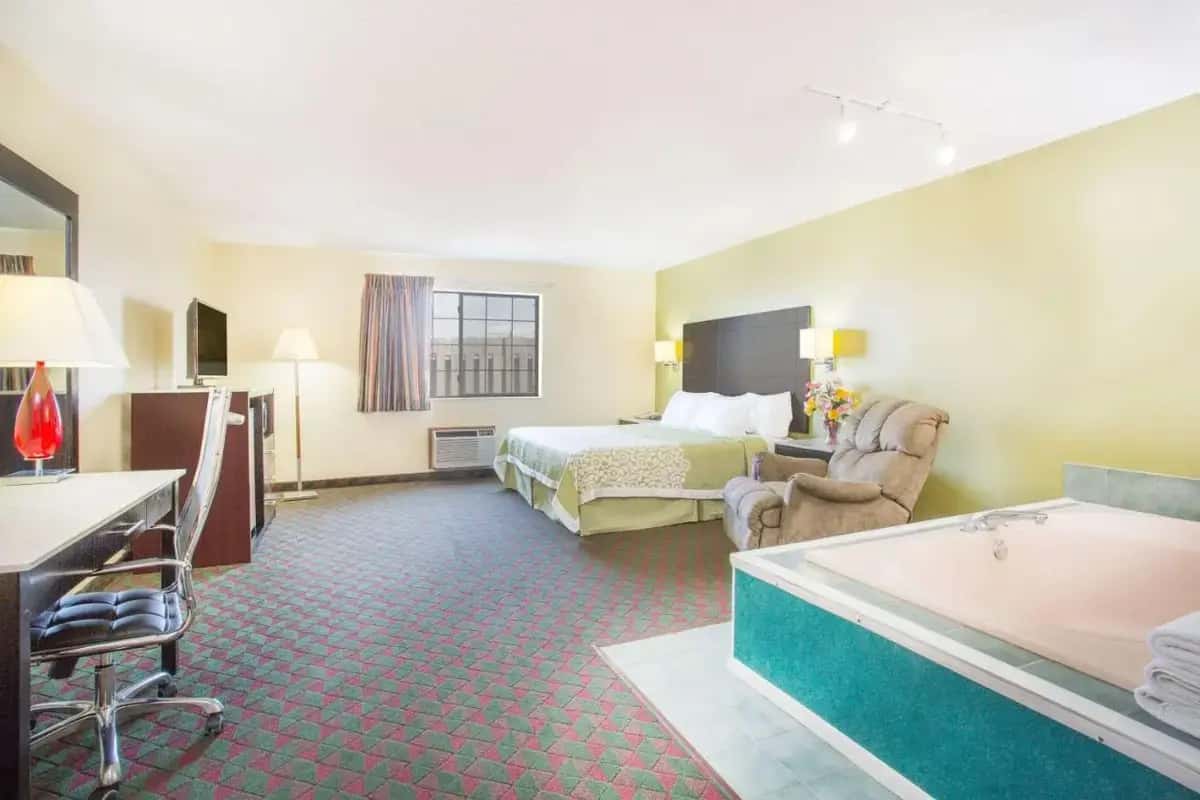 a hotel room with a bed and a bath tub at Days Inn by Wyndham Lexington NE in Lexington