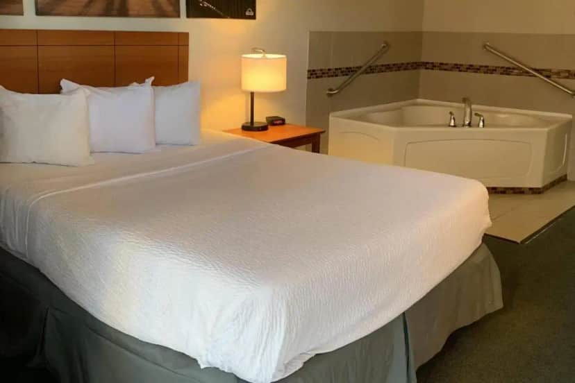 a bedroom with a large bed and a bath tub at Days Inn by Wyndham Louisville Airport Fair and Expo Center in Louisville