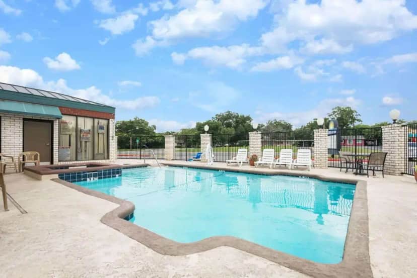 a large swimming pool with chairs and a patio at Days Inn by Wyndham New Braunfels in New Braunfels