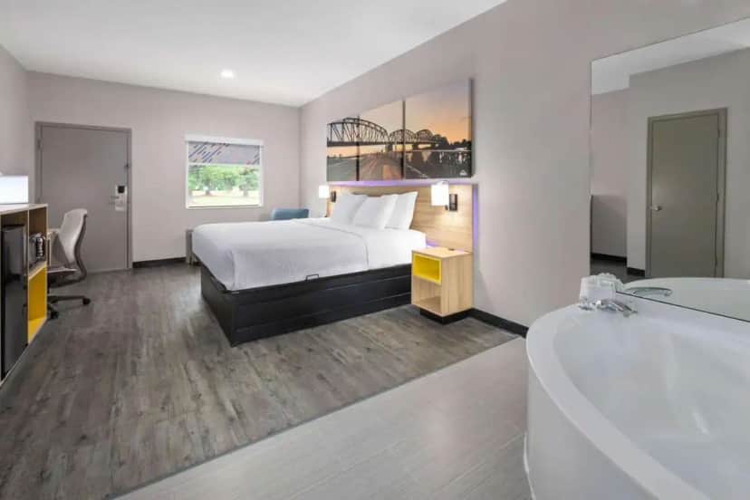 a hotel room with a bed and a bath tub at Days Inn by Wyndham North Little Rock Maumelle in Maumelle