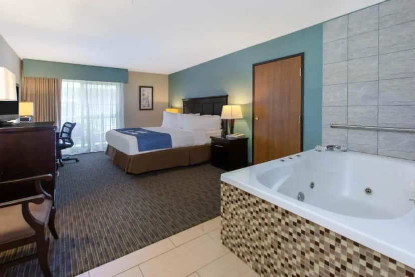 a hotel room with a bed and a bath tub at Days Inn by Wyndham Petoskey in Petoskey