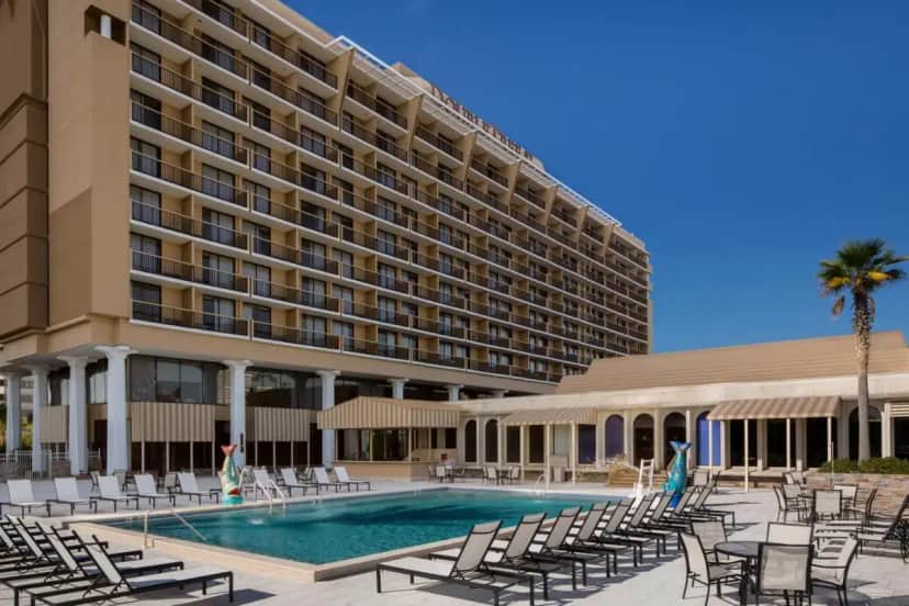 a hotel with a pool and chairs and a building at DoubleTree by Hilton Hotel Jacksonville Riverfront in Jacksonville