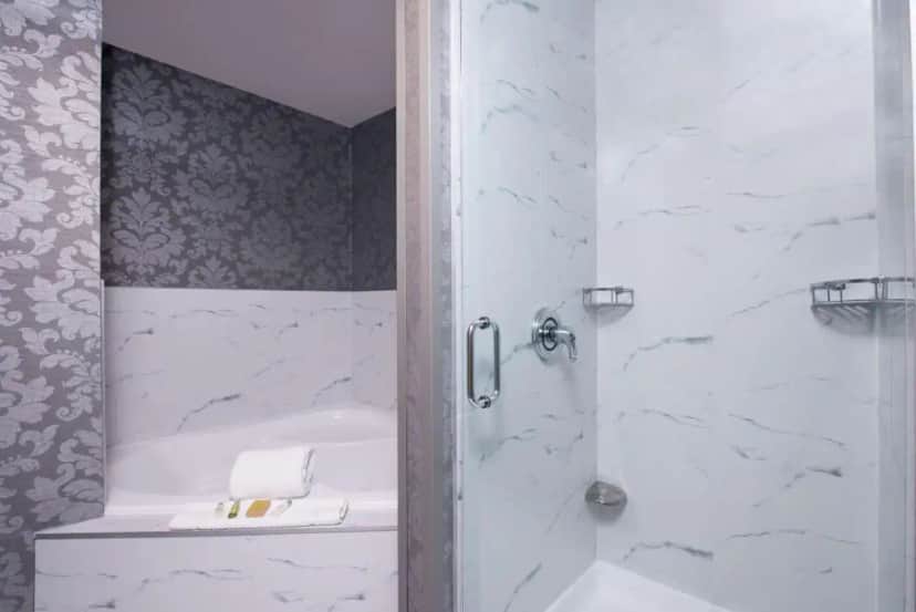 a bathroom with a shower with a tub and a sink at DoubleTree by Hilton Utica in Utica