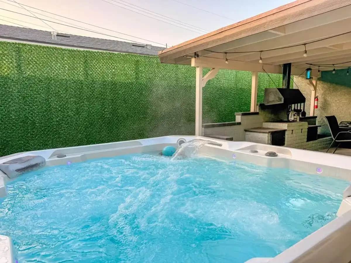 a hot tub in a backyard with a green wall at Elsa Enchanting Escape, just 8 minutes to Disney and Conventional Center in Anaheim