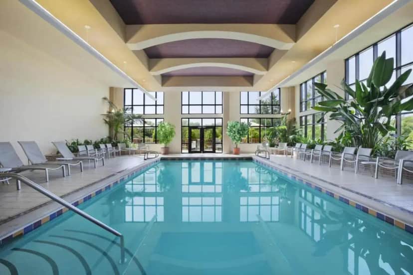 a swimming pool in a hotel with chairs and windows at Embassy Suites by Hilton at Hot Springs Convention Center in Hot Springs