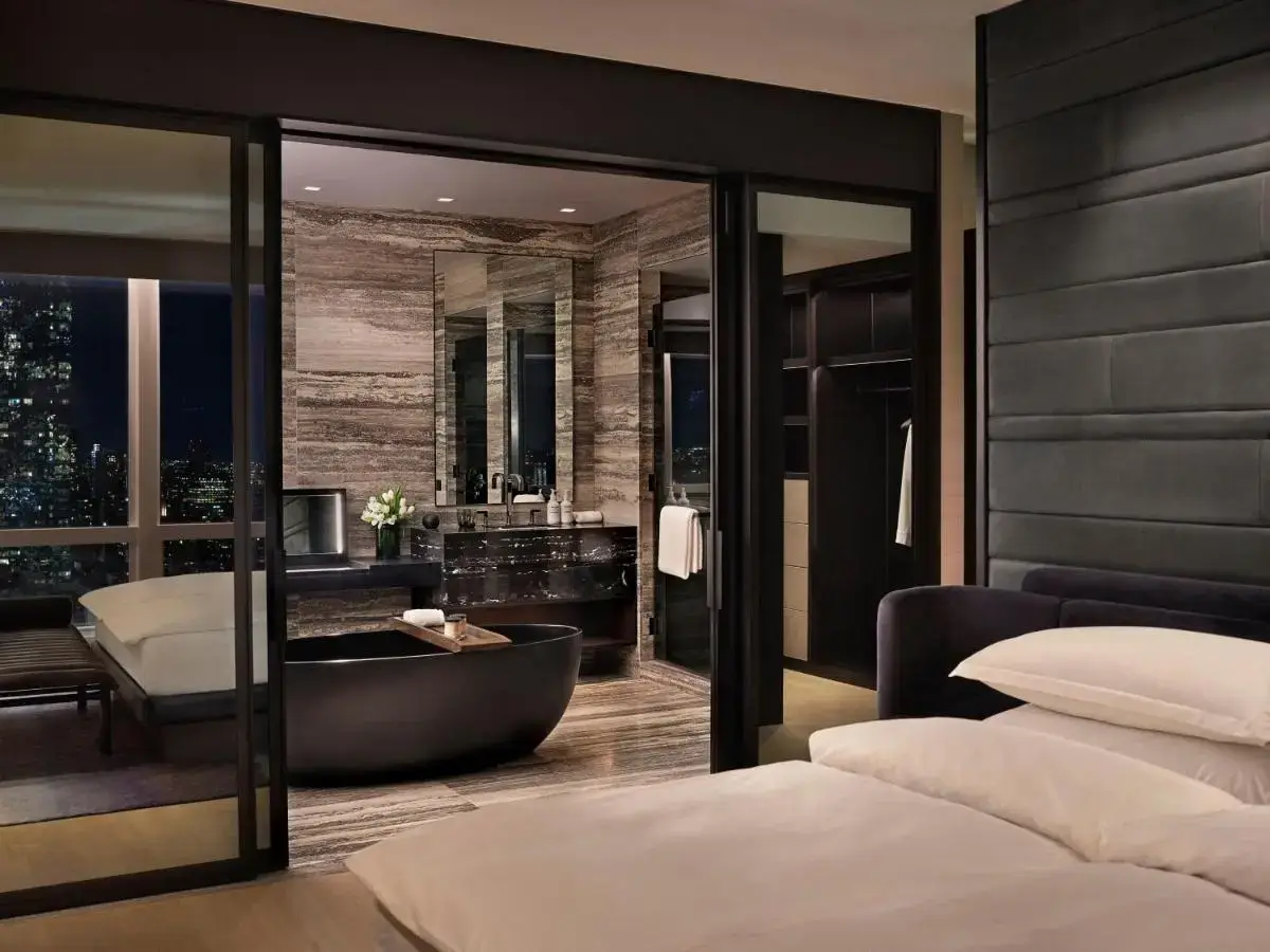 a bathroom with a bath tub and a bedroom at Equinox Hotel New York in New York
