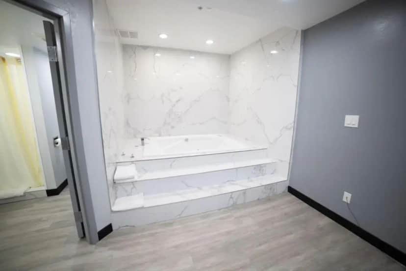 a white bathroom with a tub and marble walls at Express Inn & Suites Ontario Airport in Ontario