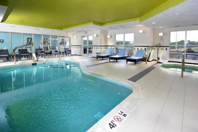 a pool in a hotel room with chairs and tables at Fairfield Inn & Suites Wytheville in Wytheville