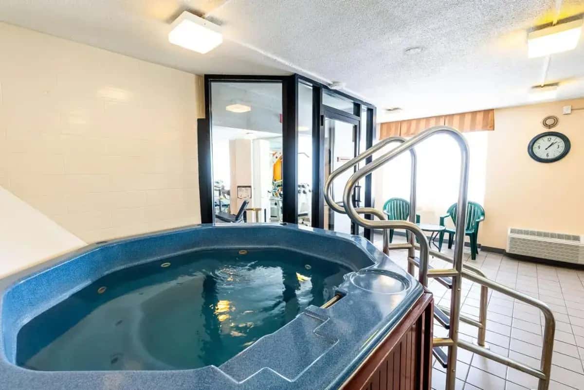 a jacuzzi tub in a room with a clock at Fireside Inn & Suites Portland in Portland