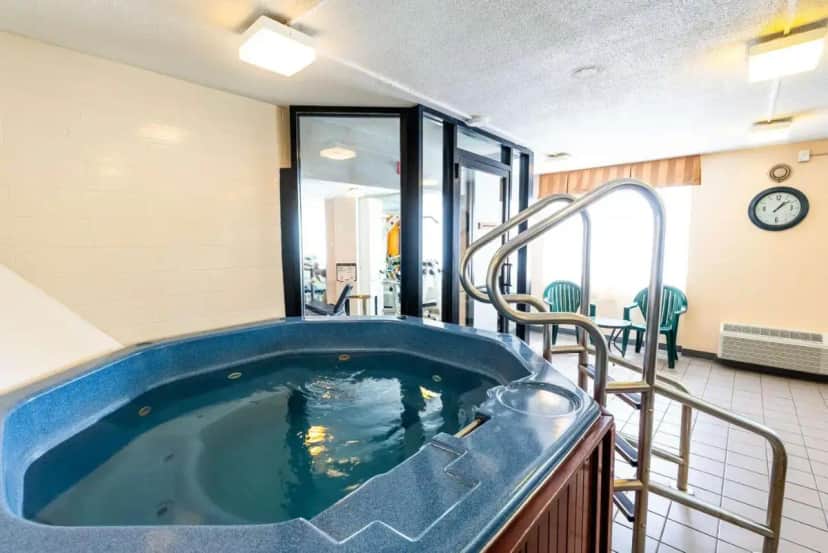 a jacuzzi tub in a room with a clock at Fireside Inn & Suites Portland in Portland