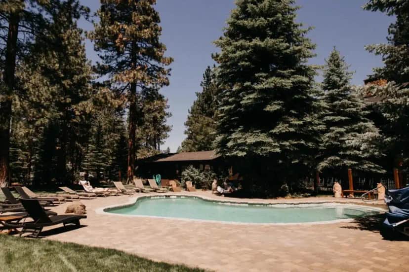 a swimming pool in a yard with chairs and trees at FivePine Lodge in Sisters