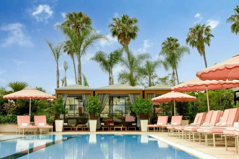 a pool with chairs and umbrellas and palm trees at Four Seasons Hotel Los Angeles at Beverly Hills in Los Angeles