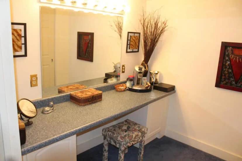 a bathroom with a counter with a mirror and a stool at Fox Creek Inn in Chittenden