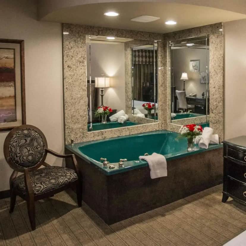 a bathroom with a tub and a chair and a mirror at Garden Place Hotel in Buffalo