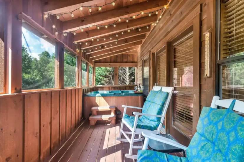a porch of a cabin with chairs and a hot tub at Goldilocks' Honey Pot in Pigeon Forge