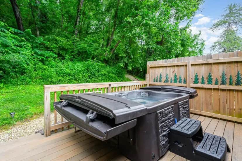a hot tub on a deck with a fence at Grey Pines at Hocking Vacations in Logan