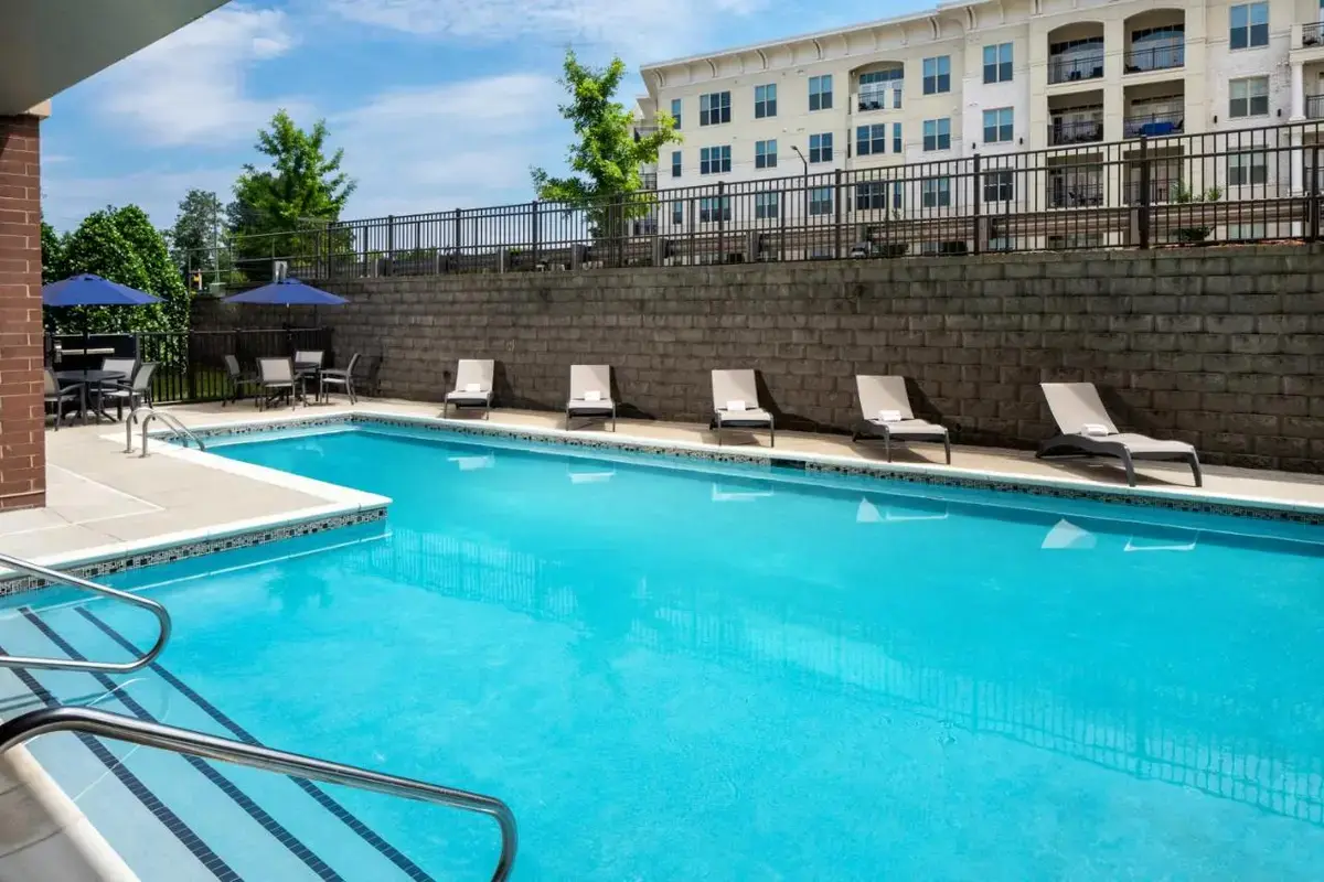 a swimming pool with chairs and a building at Hampton Inn & Suites Charlotte/Ballantyne, Nc in Charlotte