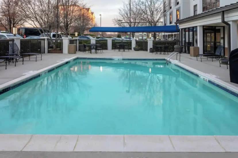 a large blue swimming pool with tables and chairs at Hampton Inn & Suites Concord-Charlotte in Harrisburg