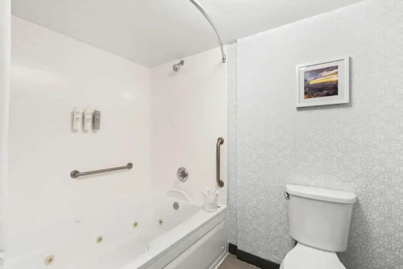 a white bathroom with a toilet and a bath tub at Hampton Inn & Suites Phoenix-Goodyear in Goodyear